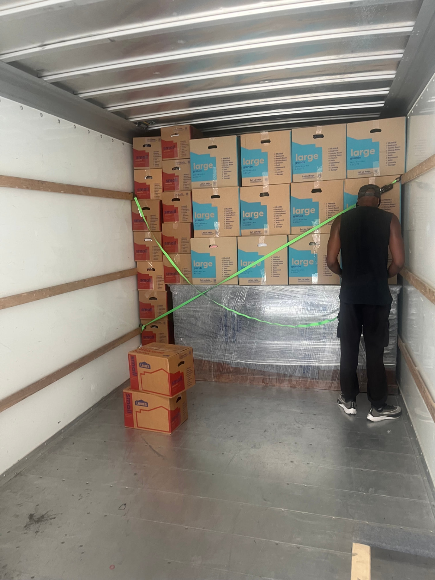 Mover strapping a stacked wall of boxes inside the truck