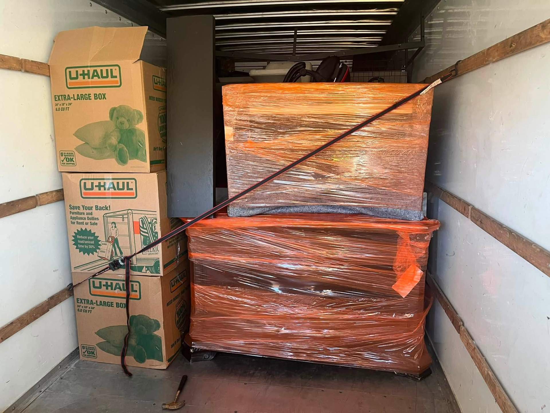 Dresser wrapped in orange stretch wrap next to labeled boxes