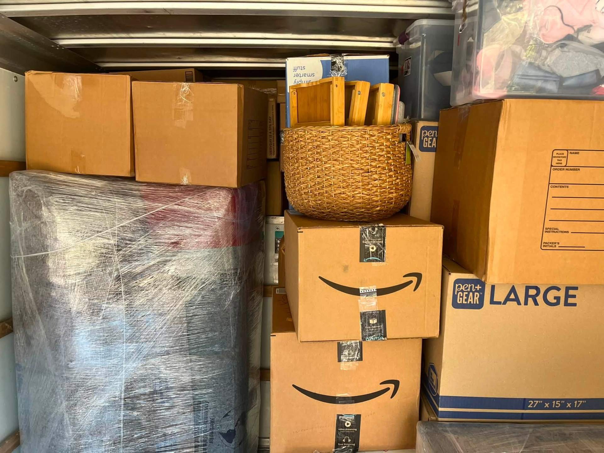 Amazon and moving boxes stacked around wrapped mattress
